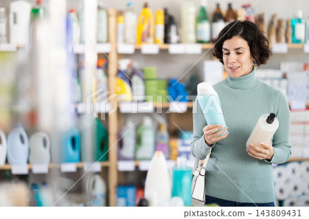 Adult woman choosing shampoo or shower gel in store 143809431