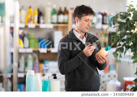 Checking expiration date of liquid hand soap - shopper scans QR code on label of liquid hand soap using smartphone Checking expiration date of liquid hand soap - shopper scans QR code on label of liquid hand soap using smartphone 143809489