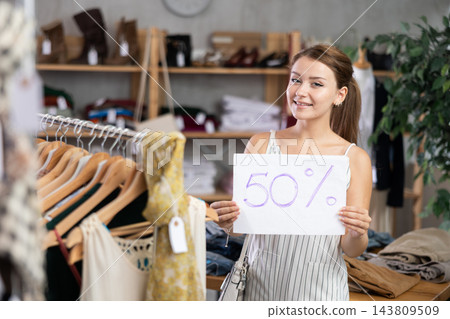 Girl with poster in hands announces discounts 50 percent in womens clothing store. 143809509