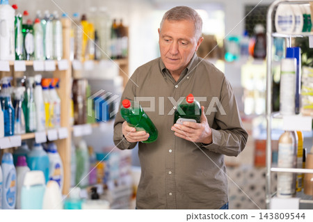 Elderly male customer diligently picking out dishwashing liquid Elderly male customer diligently picking out dishwashing liquid 143809544