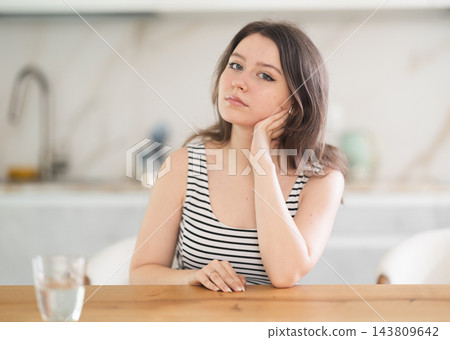 Thoughtful young woman sitting at table Thoughtful young woman sitting at table 143809642