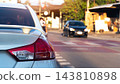 Rear view of a white car stopped on a city street during the day. Showing its detailed tail light and distant traffic on the road. Car is parked right on the red line which marks pedestrian crossing. 143810898