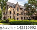 Gabled Stone Building with Arched Doorways and Green Shrubs 143810992