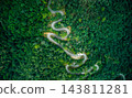 Top-down aerial view of curved road passing through lush green mountain forest 143811281
