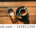 Flat lay of an espresso shot and a glass of water on a wooden table under bright sunlight 143811394