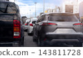 Rear view of cars and a pickup truck stuck in a traffic jam. Urban street during daylight with glowing tail lights and soft street background. Surface of car have raindrops with scattered by the rain. 143811728