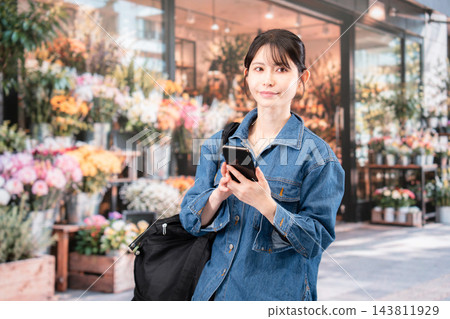 一位年輕女子邊走邊使用智慧型手機。 一位年輕女子邊走邊使用智慧型手機。 143811929