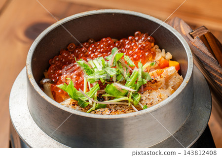 人氣菜餚「鮭魚籽釜飯」是一道以鮭魚和晶瑩剔透的鮭魚籽為特色的奢華料理。 人氣菜餚「鮭魚籽釜飯」是一道以鮭魚和晶瑩剔透的鮭魚籽為特色的奢華料理。 143812408