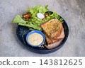 Ham and cheese grilled sandwich served with fresh salad and dipping sauce on a dark plate 143812625