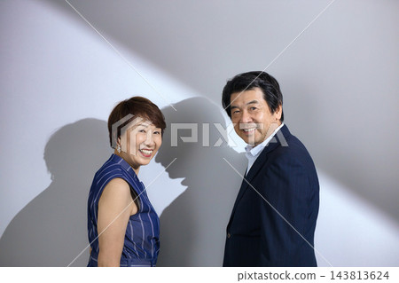 A stylishly dressed couple in their 60s, smiling and cuddling together. A stylishly dressed couple in their 60s, smiling and cuddling together. 143813624