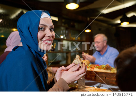 Smiling Muslim Woman in Hijab Enjoying Family Dinner at Restaurant With Multigenerational Friends Smiling Muslim Woman in Hijab Enjoying Family Dinner at Restaurant With Multigenerational Friends 143815771