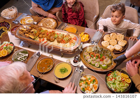Family Dinner Feast Around a Traditional Middle Eastern Table With Children and Shared Dishes 143816107