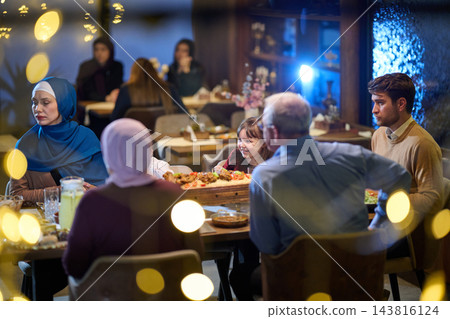 Multigenerational Family Dinner At A Cozy Restaurant With Smiling Child And Thoughtful Adults Multigenerational Family Dinner At A Cozy Restaurant With Smiling Child And Thoughtful Adults 143816124