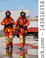 Two Firefighters In Full Protective Gear Walking From Fire Truck During Emergency Response Training 143816358