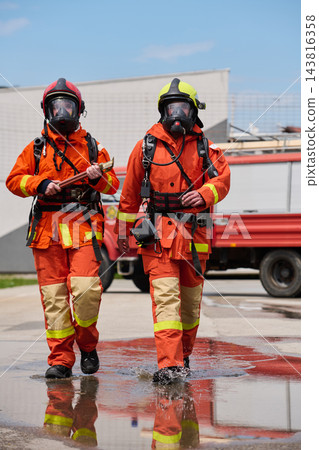 Two Firefighters In Full Protective Gear Walking From Fire Truck During Emergency Response Training Two Firefighters In Full Protective Gear Walking From Fire Truck During Emergency Response Training 143816358