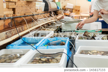 顧客在魚市的水箱裡挑選貝類時的手；購買海鮮；在市場購物。 143817133