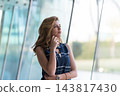 Thoughtful business woman portrait in modern glass office looking out window with confident expression 143817430