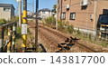 A local train line running through a residential area, with tracks and a level crossing. 143817700