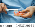 Asian senior woman patient clean teeth denture with toothbrush for chew food. 143819041