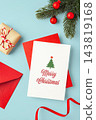 Christmas greeting card on red envelop with gift box, red ribbon and pine branch xmas ornament on blue background 143819168