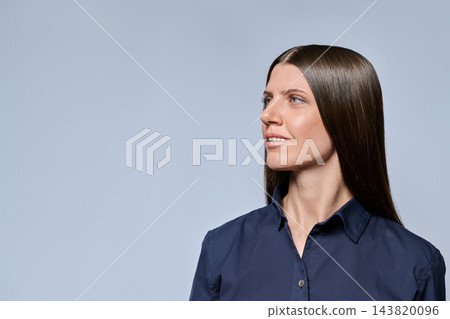 Young businesswoman in blue shirt looking up at copy space in studio Young businesswoman in blue shirt looking up at copy space in studio 143820096