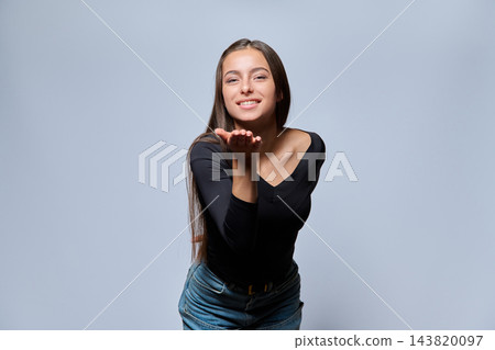 Young attractive woman blowing air kiss in studio portrait Young attractive woman blowing air kiss in studio portrait 143820097