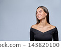 Smiling young woman looking aside to copy space on studio gray background 143820100