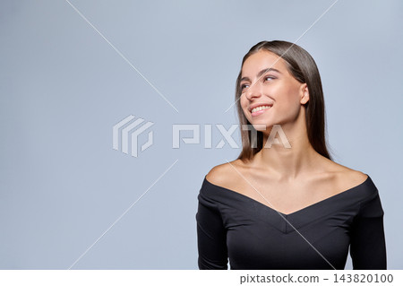Smiling young woman looking aside to copy space on studio gray background Smiling young woman looking aside to copy space on studio gray background 143820100