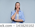 Portrait of confident smiling young woman touching chin on grey background 143820102