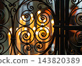 Wrought iron gate detail with blurred glowing candles in a church in France, capturing a peaceful atmosphere of faith, prayer, and reflection 143820389