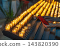 Person holding a smartphone near rows of lit votive candles inside a historic church in France, capturing a moment of quiet reflection and prayer 143820390
