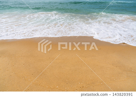 Gentle ocean waves washing over golden sand on a sunny beach in France, creating a peaceful coastal scene for summer travel and relaxation themes 143820391