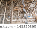 Intricate metal framework of the Eiffel Tower in Paris, France, showing industrial steel beams, rivets, and structural supports in a close-up view 143820395