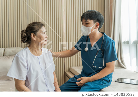 Healthcare professional consulting senior patient at home for wellness check 143820552