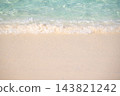 Frothy ocean wave edge spilling over smooth wet sand on sunny tropical beach during peaceful summer holiday vacation travel trip 143821242