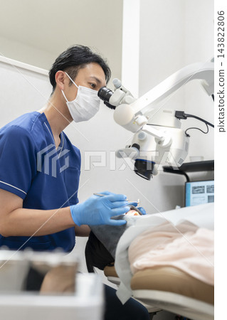 一位男牙醫正在使用顯微鏡進行檢查和治療。 一位男牙醫正在使用顯微鏡進行檢查和治療。 143822806