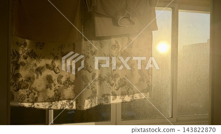 Warm sunlight shining through a window with hanging laundry and translucent fabric, creating a nostalgic cozy home atmosphere 143822870