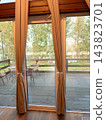 Wooden terrace with a view from the window to the garden in a glamping pod. 143823701