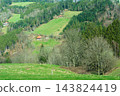 Rolling hills adorned with lush greenery and scattered wooden cottages, capturing the serene essence of rural life during a vibrant spring afternoon 143824419