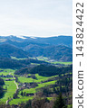 Expansive green valleys and distant snow-capped mountains create a breathtaking view of nature's beauty in springtime serenity 143824422