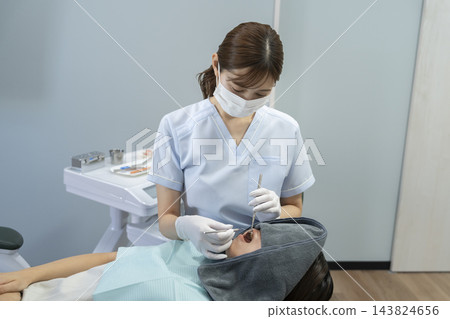 牙科保健員正在檢查患者的口腔。 牙科保健員正在檢查患者的口腔。 143824656