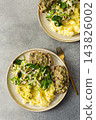 Boiled potatoes are served with hummus alongside a gluten free sandwich filled with herring mince and fresh salad on a simple plate during breakfast time 143826002
