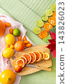 Citrus fruits are being prepared for Christmas drying. Different types of citrus are placed on a cutting board and drying rack in a home kitchen. The scene shows a festive activity 143826023