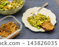 Quinoa with green peas, arugula, cauliflower, and broccoli is served with liver pate on a plate at a table during breakfast 143826035