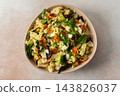 Baked chicken breast is mixed with chopped carrots, broccoli, cauliflower, and fresh herbs in a bowl. This dish is ideal for a nutritious breakfast or lunch meal 143826037