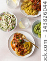 Plates hold amaranth, millet, and quinoa porridge served with baked white hake in tomato sauce. Fresh salad is beside the porridge. A bowl of kiwi sits nearby for dessert 143826044