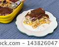 A slice of homemade gluten-free tiramisu cake with savoiardi ladyfingers and chocolate crumbs rests on a plate on a wooden table indoors 143826047
