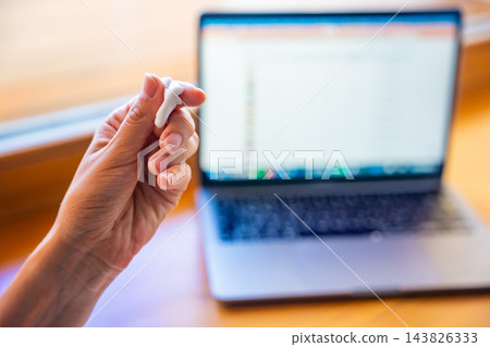 Woman squeezing stress relief putty while working at laptop. Sensory hand exercise helps reduce tension and manage stress during computer work Woman squeezing stress relief putty while working at laptop. Sensory hand exercise helps reduce tension and manage stress during computer work 143826333