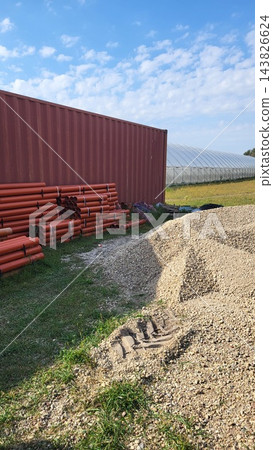 Plastic fruit crates stacked outdoors near greenhouse facility, agricultural transport and packaging supply. 143826624
