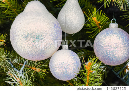 A Christmas and New Year decorated tree stands in the snow. Colorful ornaments hang from the branches, creating a festive scene during winter A Christmas and New Year decorated tree stands in the snow. Colorful ornaments hang from the branches, creating a festive scene during winter 143827325